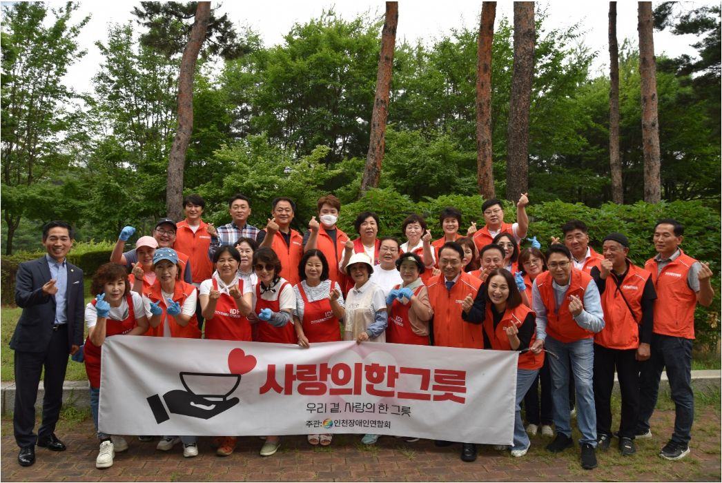 '사랑의 한그릇' 현수막을 든 연합회 회원과 봉사자들이 숲속 공원에서 함께 찍은 단체 사진